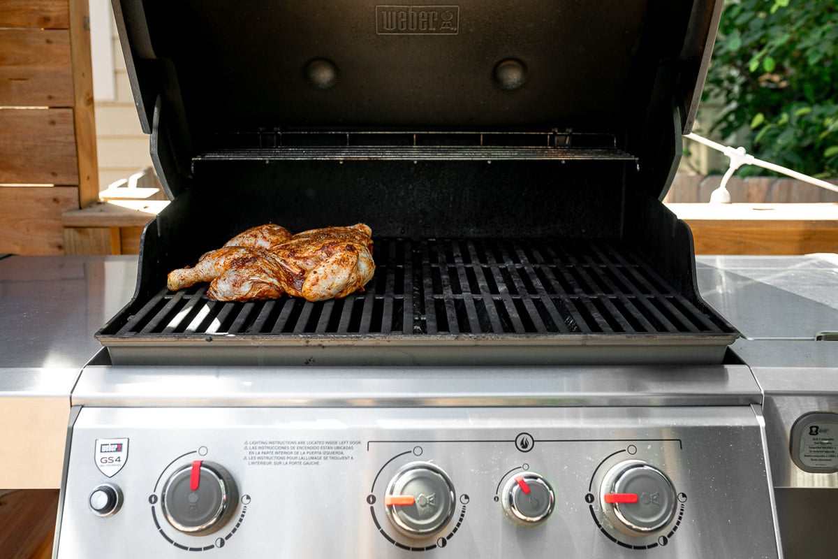 How to grill whole chicken, Step 5: Spatchcocked/butterflied chicken on grill grates, grilling in an indirect heat zone of Weber Genesis II grill.