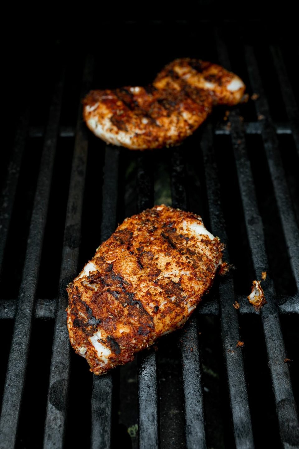 Seasoned cod fillets shown on grill grates, grilling for grilled fish tacos.