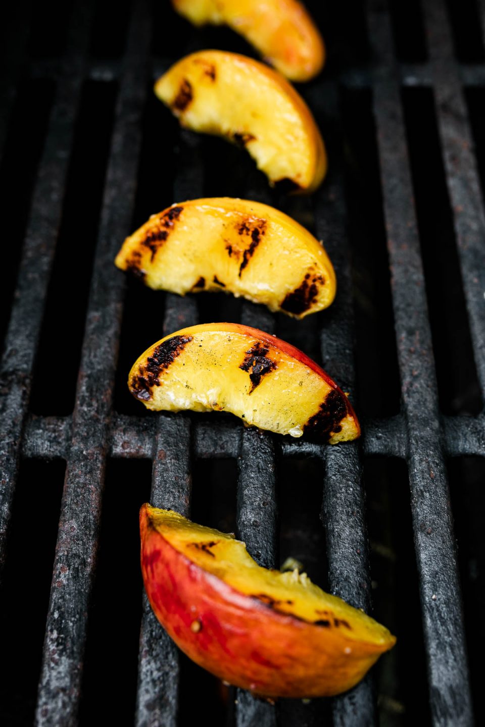Grilled peach slices directly on grill grates.