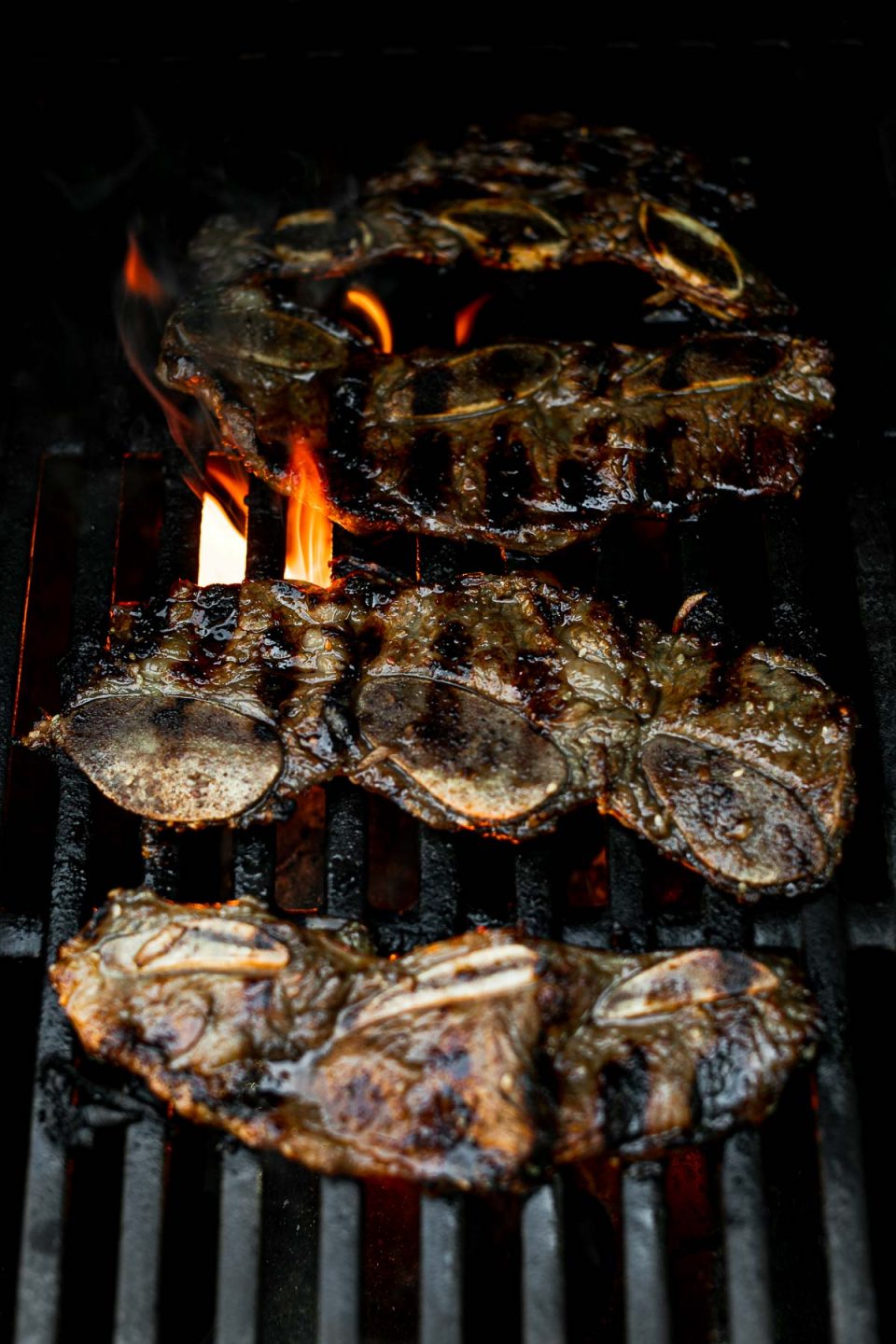 Korean beef short ribs on grill grates, grilling over direct flame.