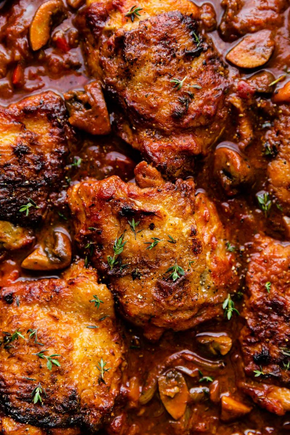 A close up of chicken cacciatore garnished with fresh thyme.