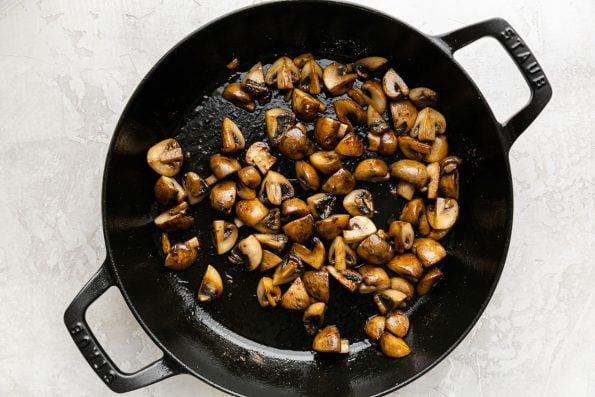How to Make Chicken Cacciatore, step 3: Mushrooms cook until browned in a heavy-bottomed cast iron pan.