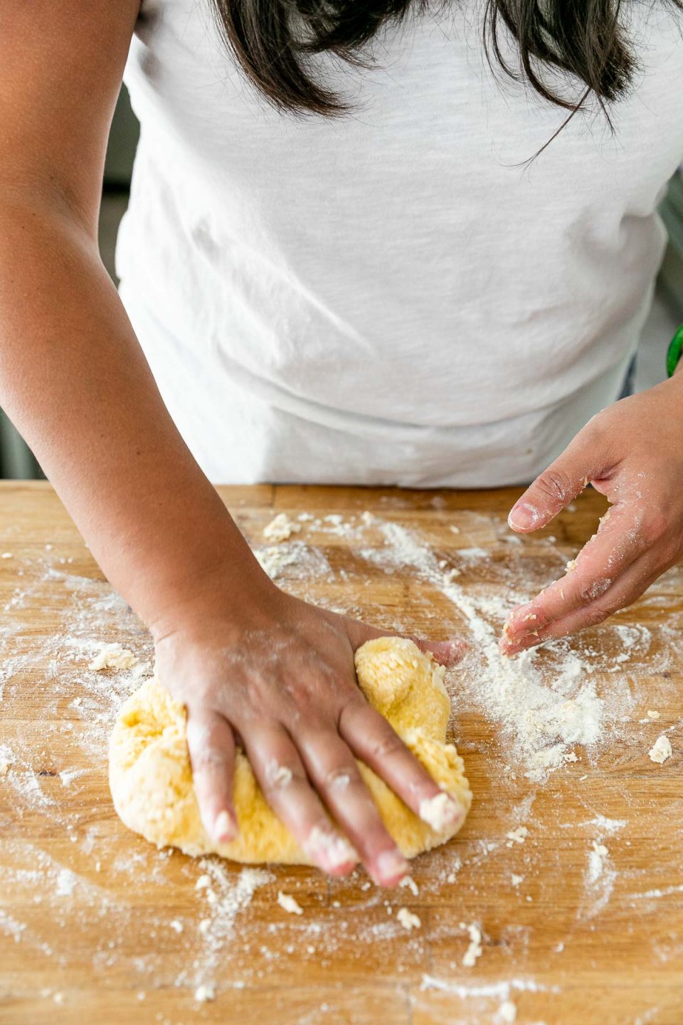 How to Make Homemade Pasta, Step 3: Knead the Pasta Dough. Jess of Plays Well With Butter uses her hands to knead the fresh pasta dough ball. The ​dough ball sits atop a butcher block countertop that is dusted with flour from the process of mixing & forming the dough ball