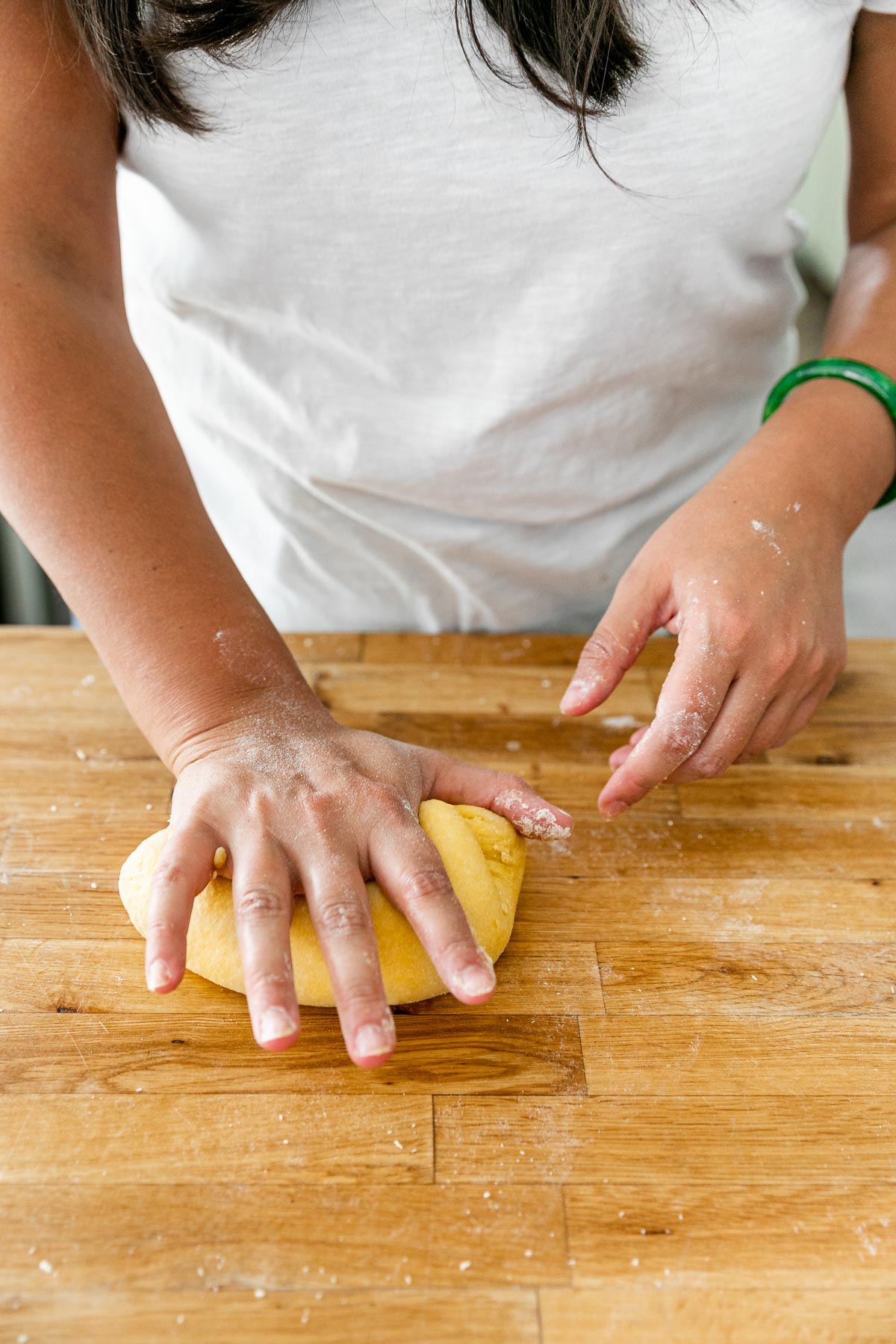 How to Make Homemade Pasta, Step 3: Knead the Pasta Dough. Jess of Plays Well With Butter uses her hands to knead the fresh pasta dough ball until it becomes smooth & supple. The ​dough ball is being kneaded on a clean butcher block countertop.