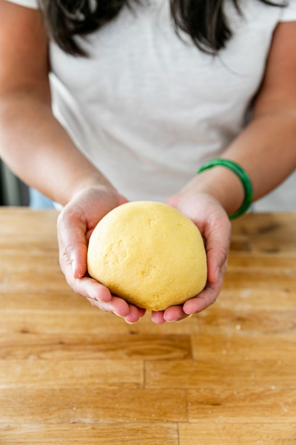 How to Make Homemade Pasta, Step 3: Jess of Plays Well With Butter holds a finished fresh pasta dough ball in both of her hands. The dough ball is smooth & supple.