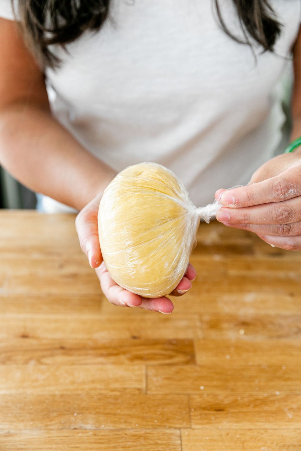 How to Make Homemade Pasta, Step 4: Rest the Pasta Dough. Jess of Plays Well With Butter holds a finished fresh pasta dough ball that has been tightly wrapped in plastic to allow it to rest.