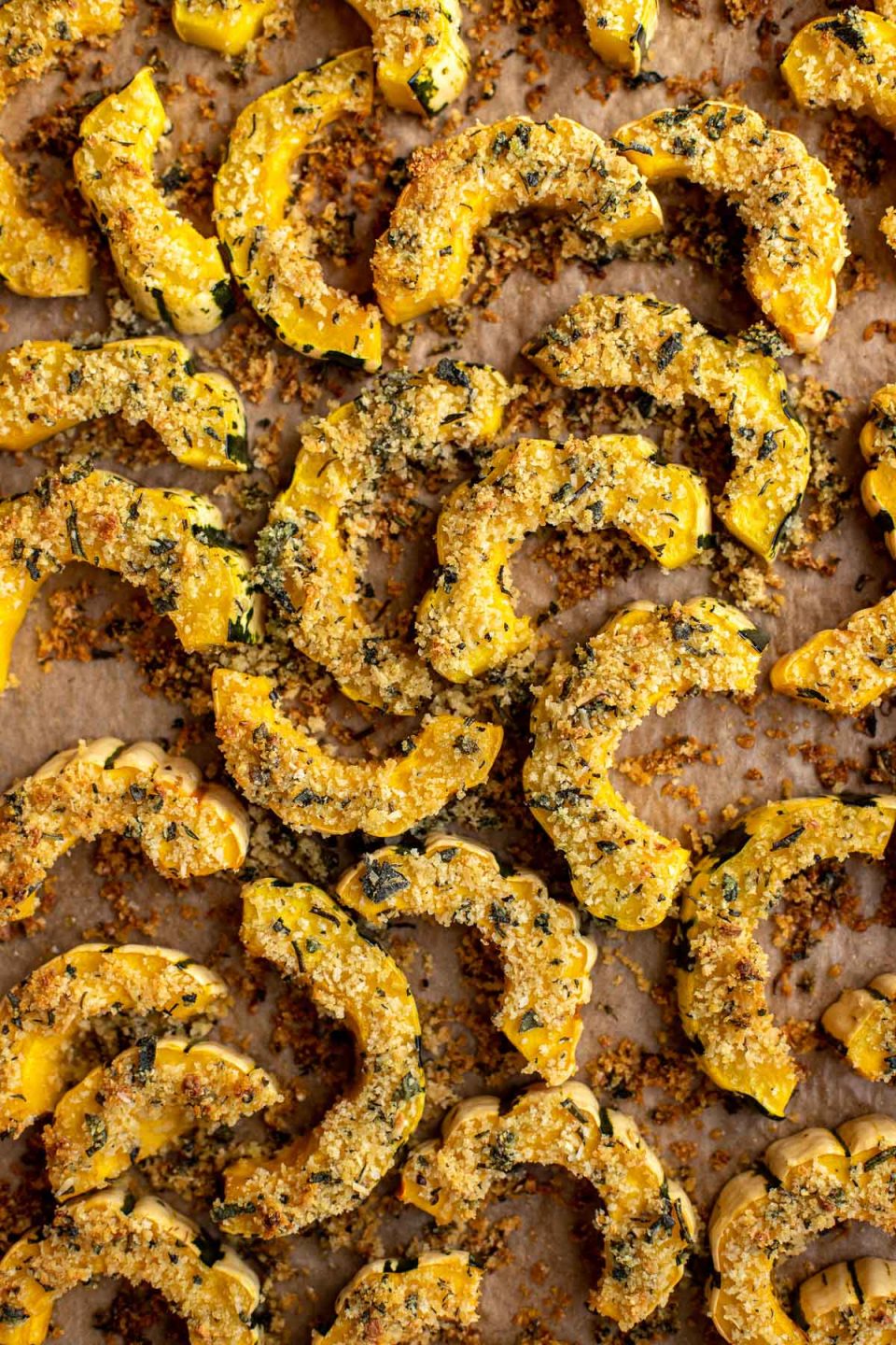 Parmesan Crusted Roasted Delicata Squash arranged on a piece of brown parchment paper.