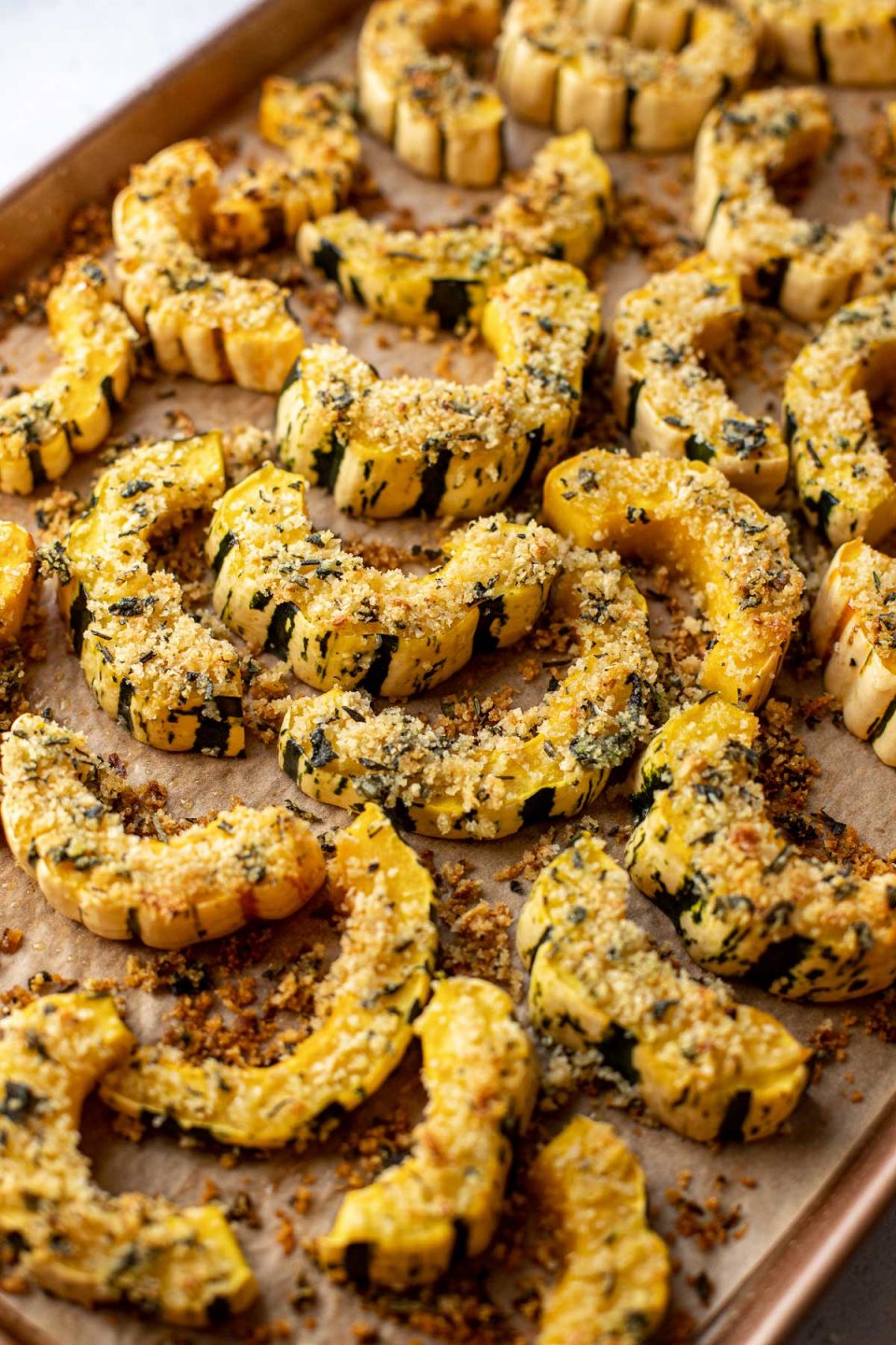 Parmesan Crusted Roasted Delicata Squash arranged on a baking sheet lined with brown parchment paper.