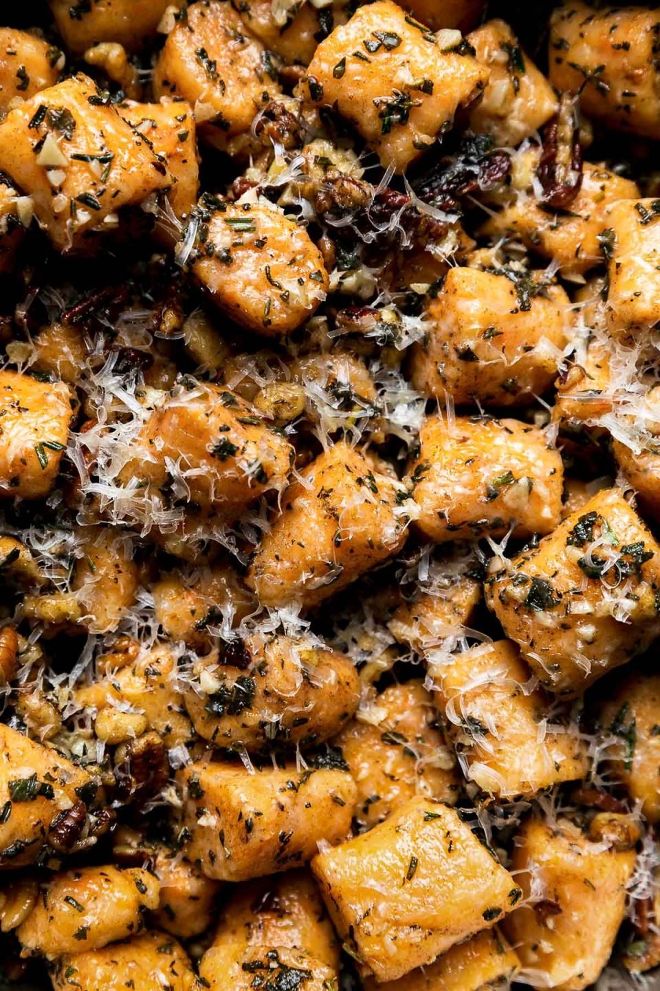 A close up of Sweet Potato Gnocchi with Garlic Herb Brown Butter sauce that has been garnished with freshly grated parmesan.