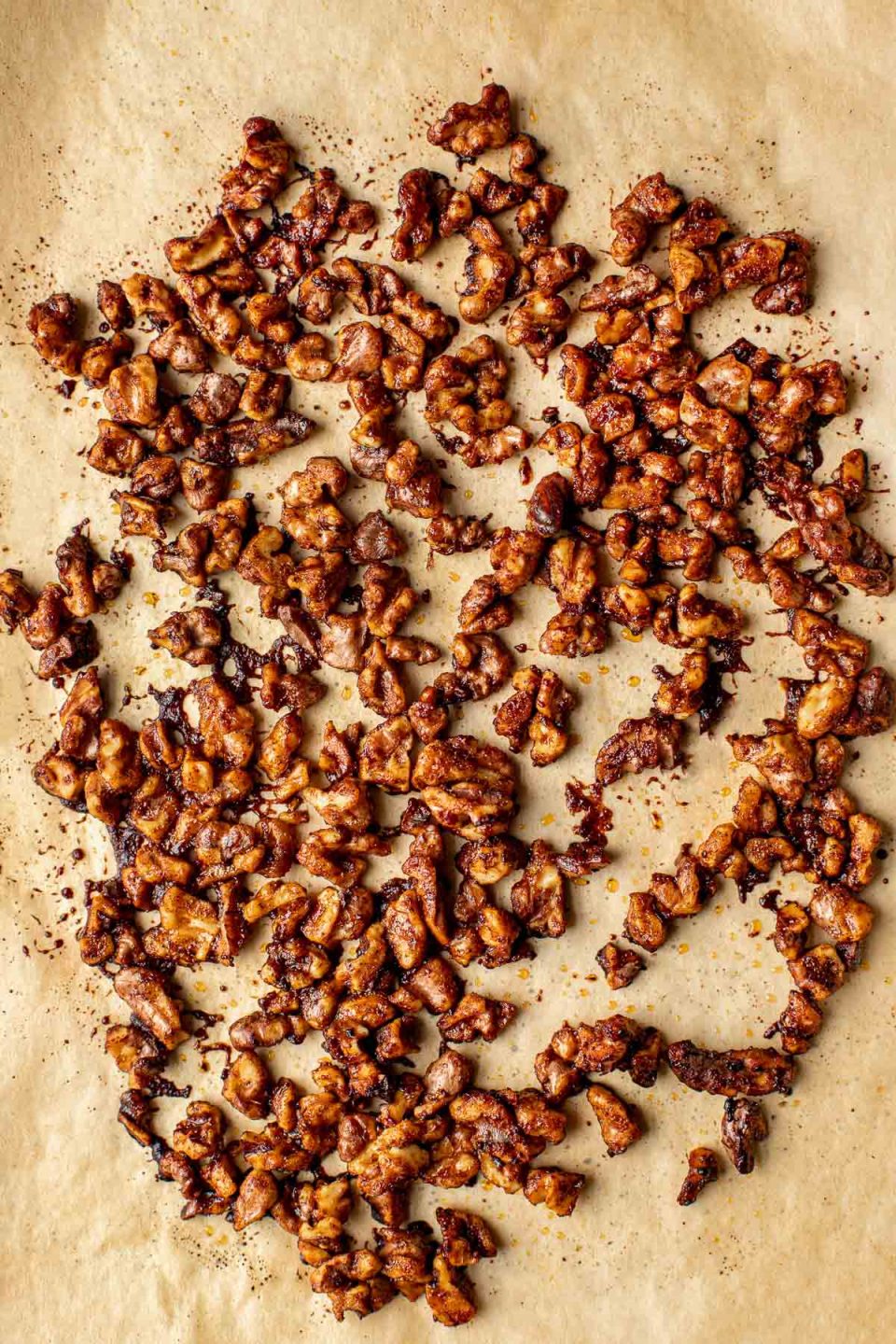 Roasted Maple Spiced Walnuts rest atop a piece of brown parchment paper.