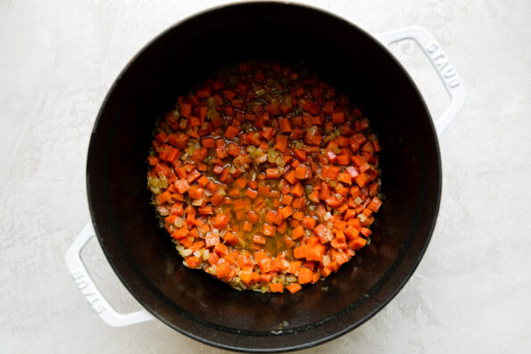 How to make Ribollita soup, step 2: Cook the aromatics. Softened carrots, celery, onion seasoned with Italian seasoning & deglazed with white wine fill a white Staub cocotte.