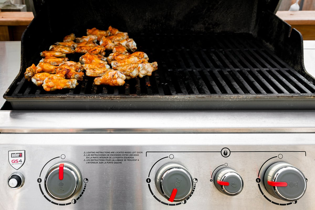 How to grill chicken wings, step 3: Grill the wings with indirect heat. Brined chicken wings are placed over the an indirect heat section of a gas grill for cooking.