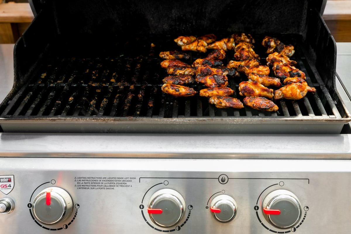How to make grilled wings, step 4: Char the wings over direct heat. Grilled buffalo wings arranged on a gas grill over direct heat to finish cooking them and achieve a char grill.