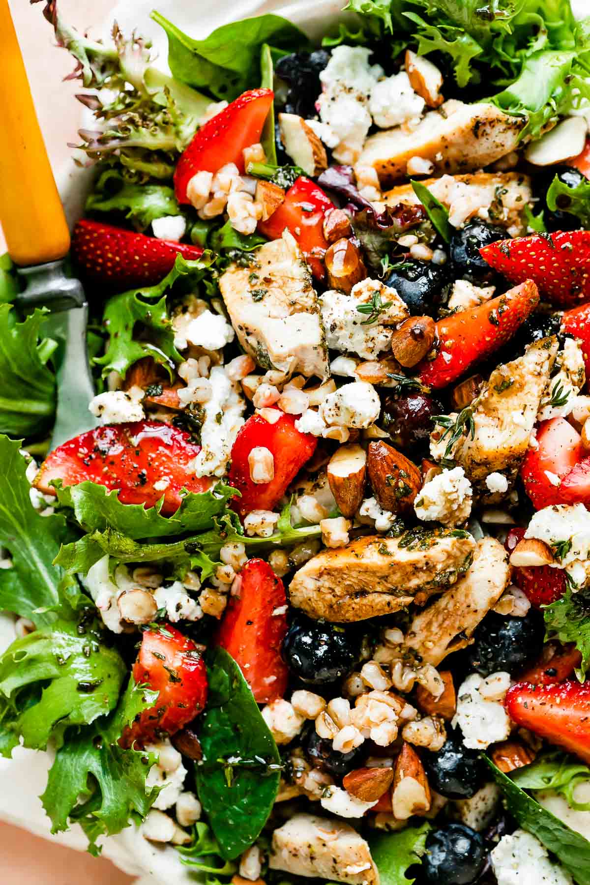 An up-close macro shot of the strawberry chicken salad: greens, strawberries, chicken, almonds, goat cheese and vinaigrette.