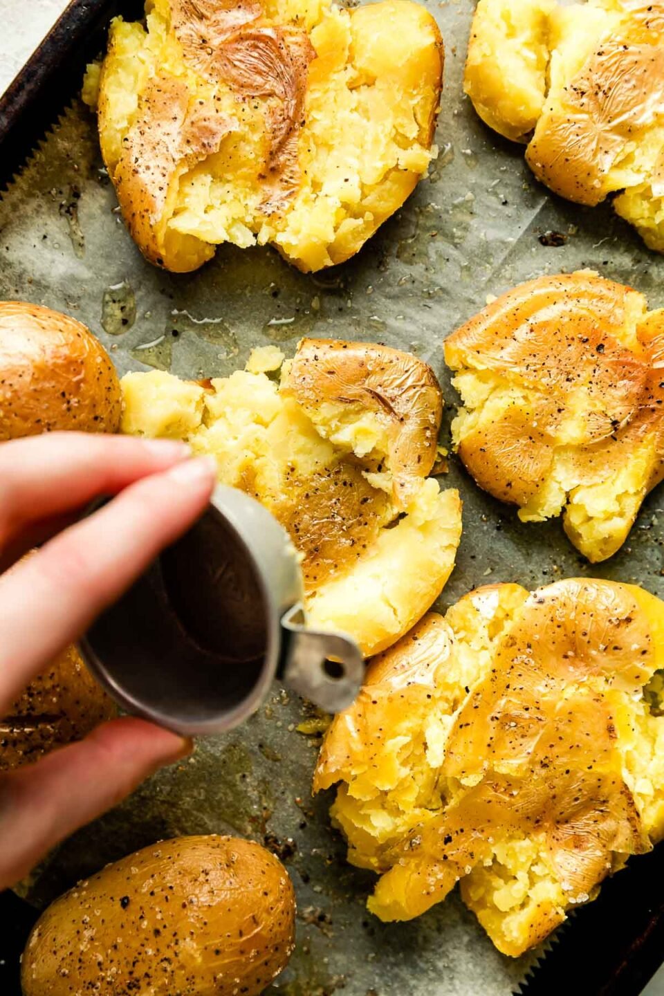 Crispy smashed potatoes are arranged atop a baking sheet lined with parchment paper.