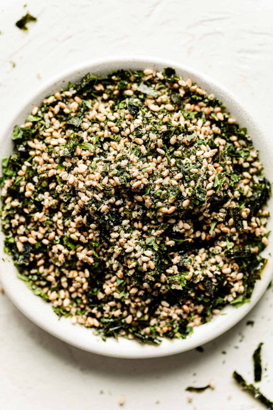 A close-up overhead shot of a bowl of furikake on a white textured surface.