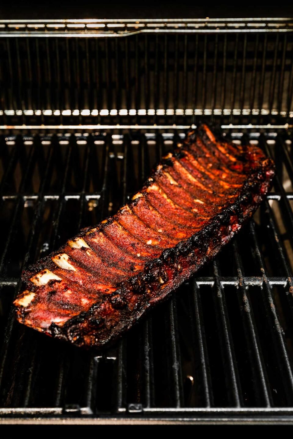 A close-up shot of the grill with a rack of cooked baby back ribs.