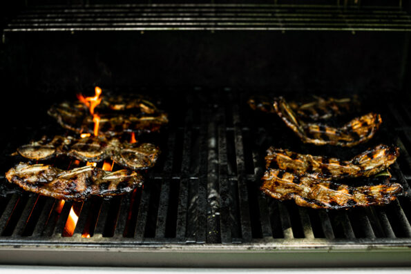 Korean beef short ribs on grill grates, grilling over direct flame.