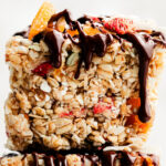 A close-up macro side shot of a muesli bar with chocolate drizzle dripping down the side.