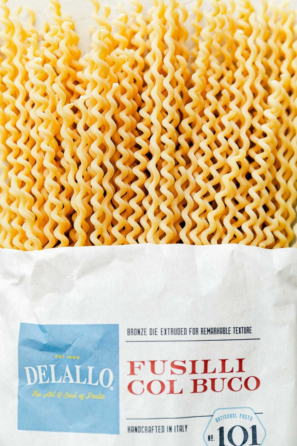 A close-up shot of dry fusilli pasta halfway out of a bag.