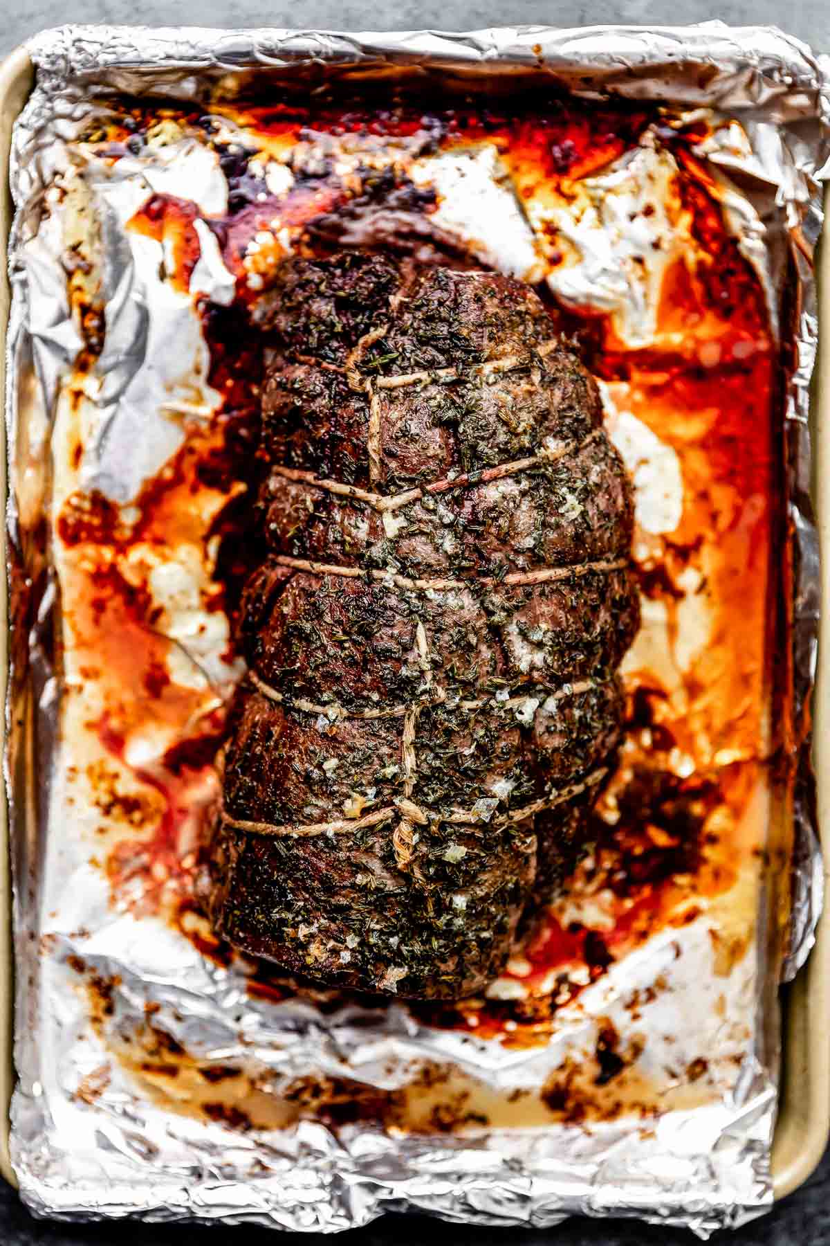 An overhead shot of a roasted beef tenderloin on a foil-lined sheet pan.
