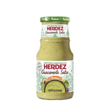 A glass jar of Herdez Guacamole Salsa, labeled Medium. The jar contains green salsa and features images of avocado and peppers on the label, with text in both English and Spanish.