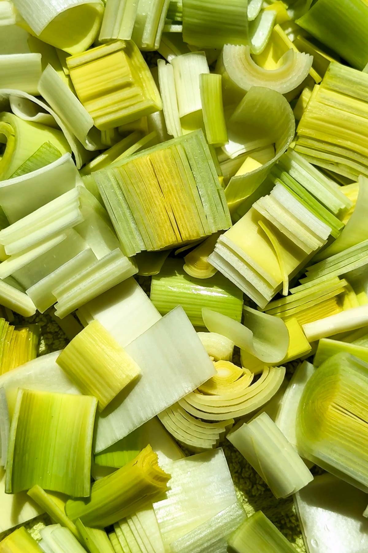 Close-up of chopped leeks in various shades of green and white, showing their layered texture and natural patterns.