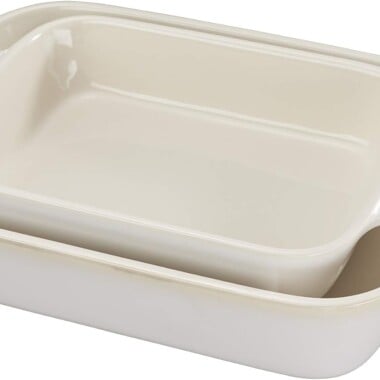 Two rectangular off-white ceramic baking dishes with Staub branding on the handles, nested inside one another.